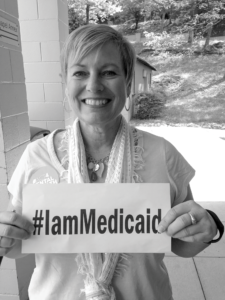 A woman holding an #IamMedicaid sign