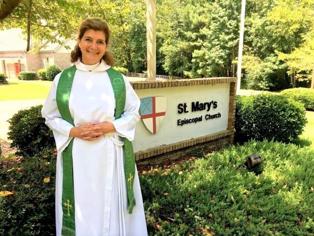 Rev. Robin Hinkle stands in front of the sign for St. Mary's Episcopal Church