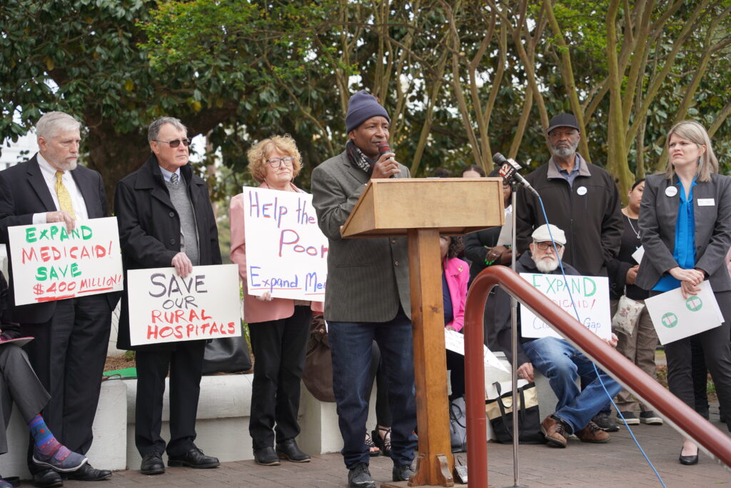 A man stands at a podium to give a speech on Medicaid expansion.